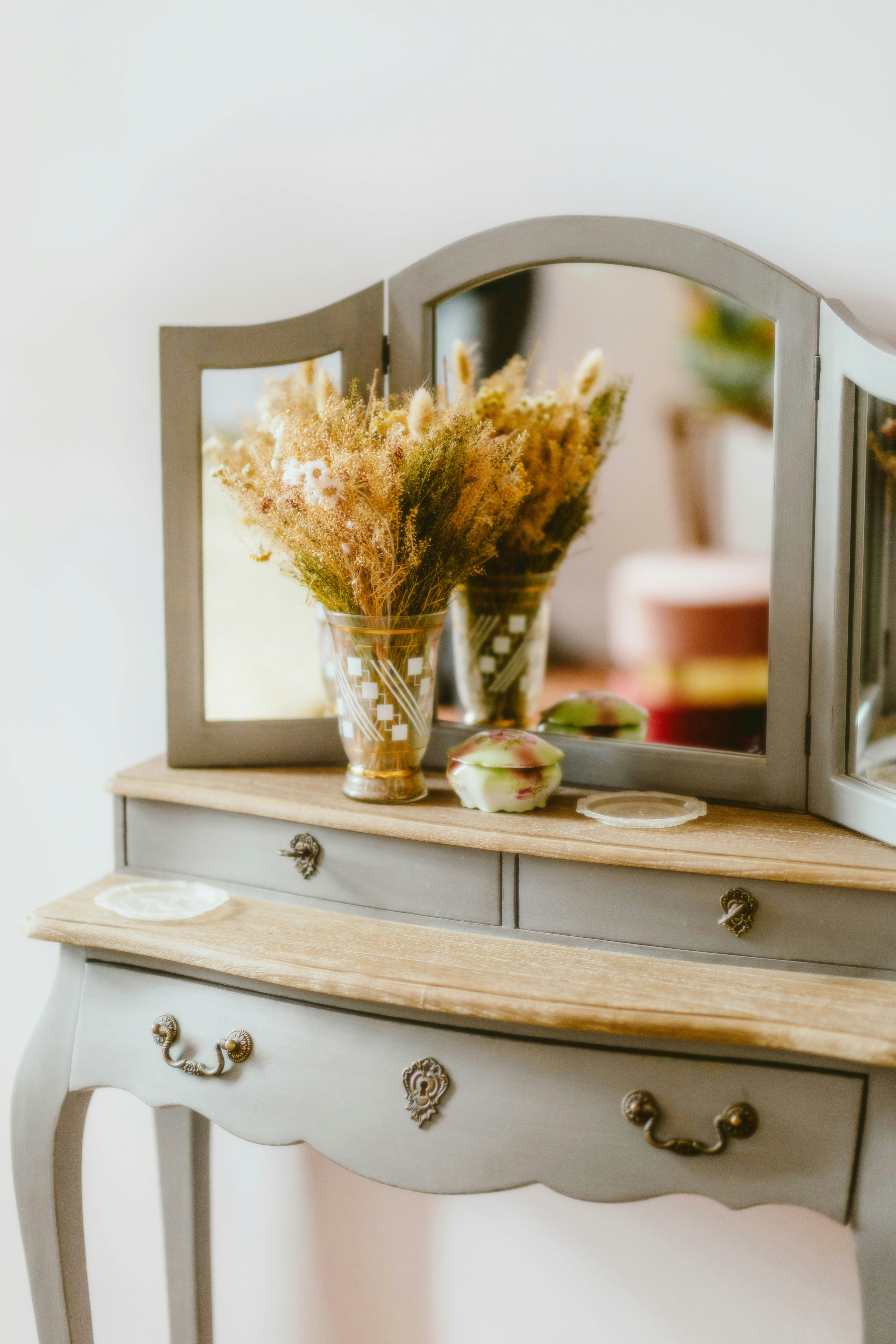 A table with a mirror and a vase of flowers on it